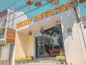 uma loja ensolarada à beira do rio com um sinal na porta em Sunny Riverside Homestay em Hoi An