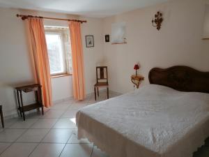 een slaapkamer met een bed en een raam met oranje gordijnen bij Gîtes Mas de la Musardière in Les Assions