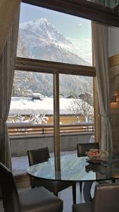 uma mesa e cadeiras em frente a uma janela com uma montanha em Chalet Champion 1 em Chamonix-Mont-Blanc