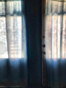 eine Tür mit Vorhängen neben einem Fenster in der Unterkunft Hostal mandala Evelyn in El Pacífico