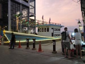 a group of people standing around a boat in front of a building at Green​ house​ Samui in Bophut 