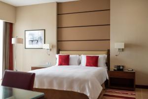 a hotel room with a large bed with red pillows at Khalidiya Palace Rayhaan by Rotana, Abu Dhabi in Abu Dhabi