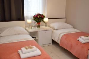 two beds in a room with towels and a vase of flowers at Cracow Central Aparthotel in Krakow