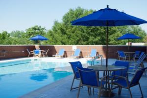 a pool with tables and chairs and blue umbrellas at Holiday Inn Arlington at Ballston by IHG in Arlington
