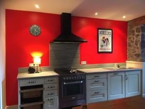a kitchen with a stove and a red wall at alpine apartment in Les Gets