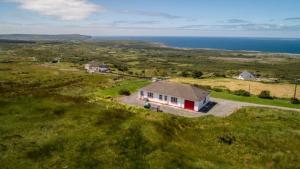 uma pequena casa em um campo próximo ao oceano em Atlantic Rose Cottage em Doolin