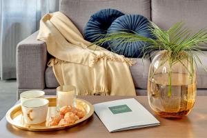 a coffee table with a plate of food and a vase at Premium Residence by Welcome Apartment in Gdańsk