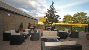 eine Terrasse mit Sofas und Stühlen und einem Weihnachtsbaum in der Unterkunft Holiday Inn Huntingdon Racecourse, an IHG Hotel in Huntingdon