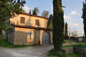 una vieja casa de piedra con una puerta y un árbol en Giaggiolo, en Poggibonsi