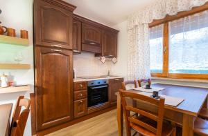 una cucina con armadi in legno e un tavolo in legno con sala da pranzo di Moderno Appartamento Tarvisio - A due passi dalla Ciclovia! a Tarvisio