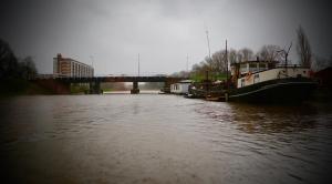 a boat is docked on a river with a bridge at B&B De Leeuw in Zwolle