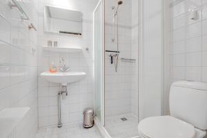 a white bathroom with a toilet and a sink at Ferienhaus Petten aan Zee in Petten +17 photos