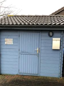 a blue garage with a white door and a roof at Beachcomber House A in Friedrichskoog