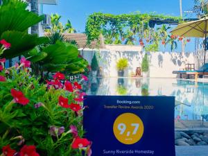 um sinal em frente a uma piscina com flores em Sunny Riverside Homestay em Hoi An