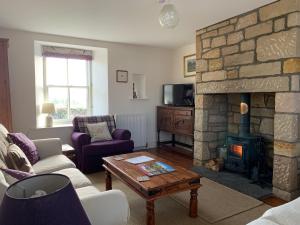 a living room with a stone fireplace and a table at Charming cottage with loch and hill views nr Edinburgh in Cobbinshaw