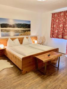 Un dormitorio con una gran cama de madera y una mesa. en AlpenChalet Mitterberg, en Mariapfarr