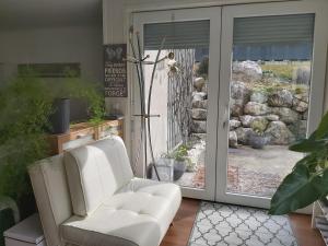 ein Wohnzimmer mit einem weißen Stuhl und einer Glasschiebetür in der Unterkunft Relax-Apartment mit Sauna in Klagenfurt am Wörthersee