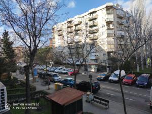 un estacionamiento con autos estacionados frente a un edificio en Habitación JC en Madrid