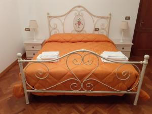 een bed met een oranje dekbed en twee nachtkastjes bij La Fiora in Sansepolcro