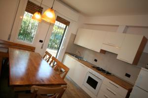 uma cozinha com uma mesa de madeira e armários brancos em BA - VILLA LUCY - Single Villa - em Lignano Sabbiadoro