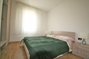 um quarto com uma cama com um edredão verde e uma janela em BA - VILLA LUCY - Single Villa - em Lignano Sabbiadoro
