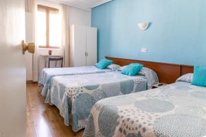 Duas camas num quarto com paredes azuis em Hostal Rober em Madrid