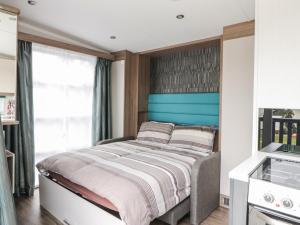 1 dormitorio con 1 cama con cabecero azul en Cabin at the Tavern en Blairgowrie