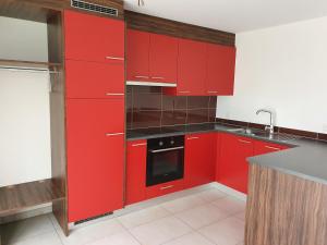 a red kitchen with red cabinets and a sink at Gîte La Broye in Surpierre