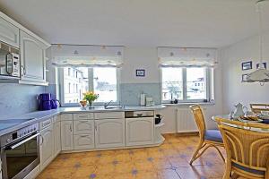 a kitchen with white cabinets and a table and chairs at Villa Seestern _ Wohnung 10 in Neuhof