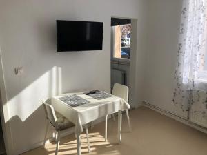 une table blanche avec des chaises et une télévision murale dans l'établissement Apartment in EG Schaupenstiel, à Northeim