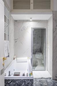 uma casa de banho branca com uma banheira e um espelho. em Domus Nannini SPA - L' Arco di Matteotti em Siena