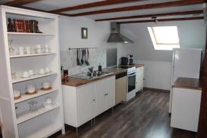 a kitchen with white cabinets and a sink and a refrigerator at Grand Gite Angelique avec Jardin - Centre Ribeauvillé in Ribeauvillé