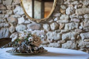 a vase with flowers on a table in front of a stone wall at Torre della Loggia - Dimora Storica - Ortona in Ortona