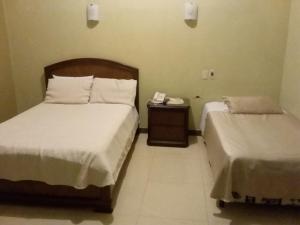 Un dormitorio con 2 camas y un teléfono en una mesa. en Hostal Cristhian Inn, en Guayaquil