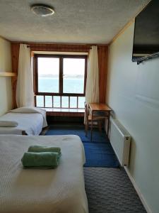 a room with two beds and a desk and a window at Laguneclub - Su casa de campo in Frutillar