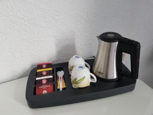 a black tray with a coffee pot and a tea kettle at Pension Am Stadtrand in Leipzig