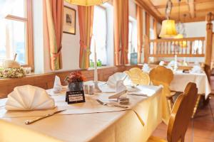 ein Esszimmer mit weißen Tischen, Stühlen und Fenstern in der Unterkunft Hotel Restaurant Erber in Ismaning