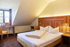 Schlafzimmer mit einem großen Bett mit einem Kopfteil aus Holz in der Unterkunft Hotel Restaurant Erber in Ismaning