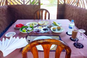 a table with plates of food and drinks on it at Dew Safari Cottage in Udawalawe