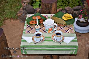 a table with two cups of coffee and a plate of food at Elephant Lovers Inn in Pinnawala