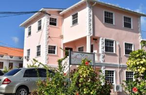 un edificio rosa y blanco con un coche aparcado delante en Aanola Villas 6b Tranquil Privy Boudoir en Charlotte