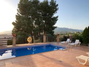 una piscina con 2 sillas y un árbol en Casas Rurales Cazorla-Alcón, en Pozo Alcón