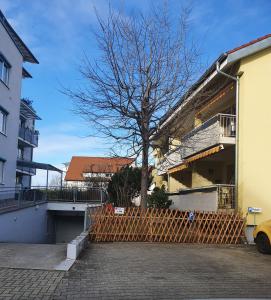 uma árvore em frente a um edifício com uma cerca em Business Apartment in Weil am Rhein em Weil am Rhein