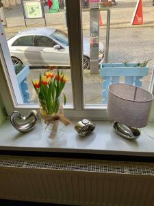 een vensterbank met een vaas met bloemen en een klok bij Bluhm's Hotel & Restaurant am Markt in Kyritz