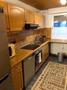 a kitchen with wooden cabinets and a stainless steel sink at Ferienwohnung Bodensee LA in Langenargen +5 photos