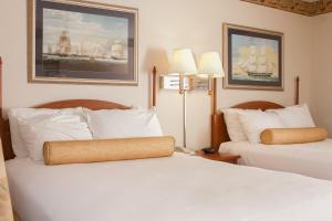a hotel room with two beds and two paintings at Flagship Inn in Boothbay Harbor