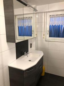 a bathroom with a sink and a mirror and blue curtains at Ferienwohnung Bodensee LA in Langenargen
