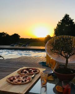 duas pizzas sentadas numa mesa com o pôr-do-sol ao fundo em La Belle Landaise 1809 Gîte Arridoulet 2 em Peyrehorade