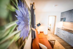 a living room with an orange couch and a blue flower on the wall at Rauchenbichlerhof in Brunico