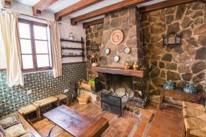Habitación de piedra con chimenea y mesa en tuGuest Country House Monachil, en Granada
